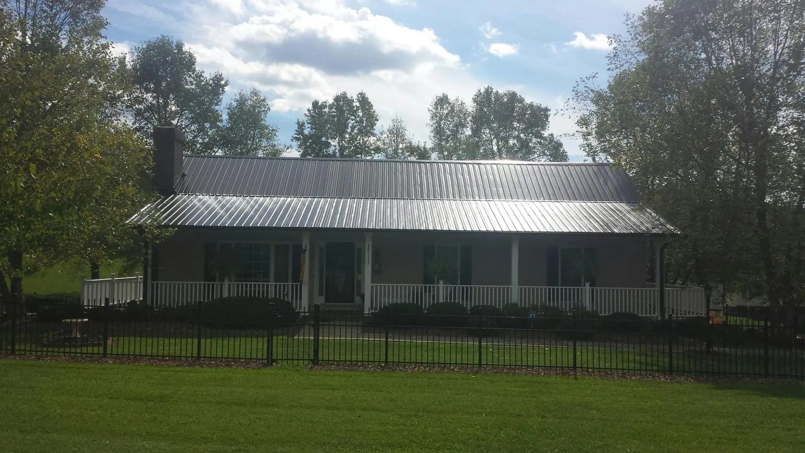 Gray metal roof on a brick ranch with a full width front porch — Gutter Guard Installation work by our crew in Florissant