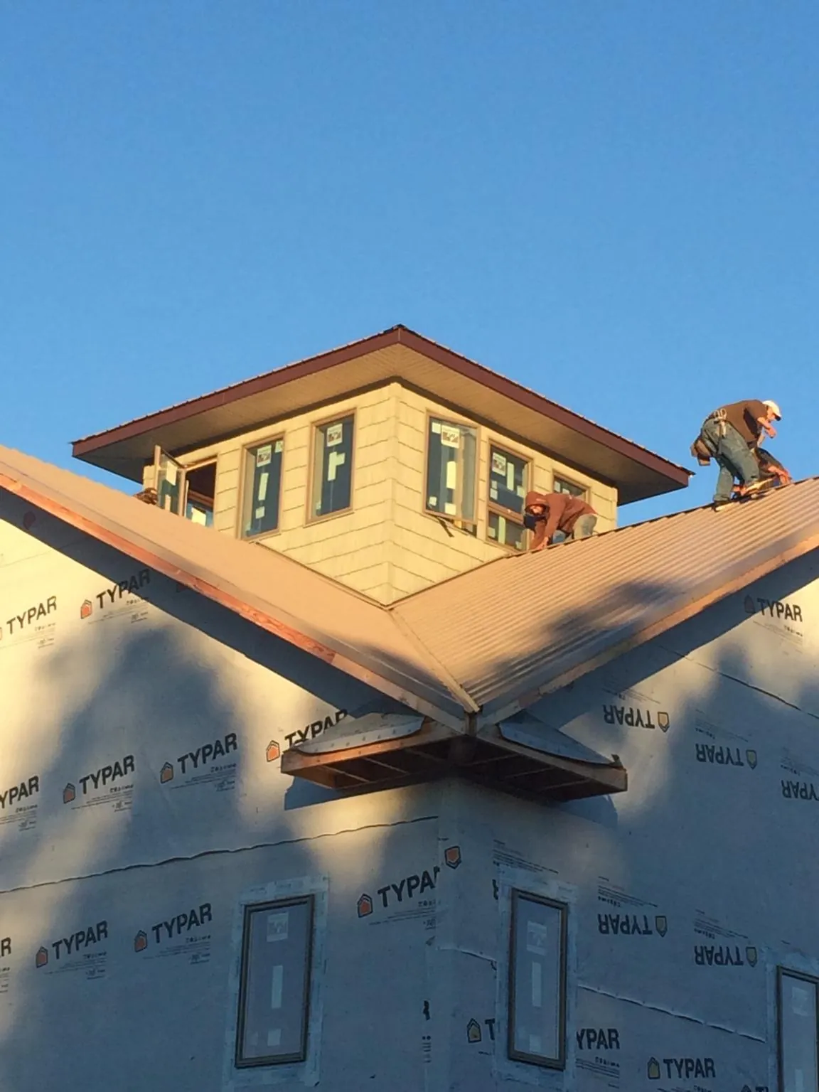Roofers working around a rooftop cupola on a new metal roof at sunset — Roof Waterproofing in Florissant by Roofing Brothers